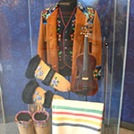 A clear display case featuring Métis clothing.