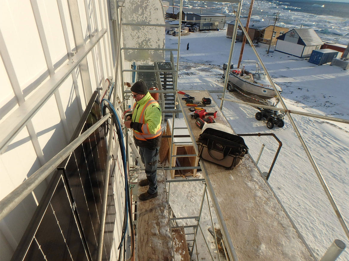 Michael Schneider travaille à l’installation de panneaux solaires sur le côté d’un bâtiment.