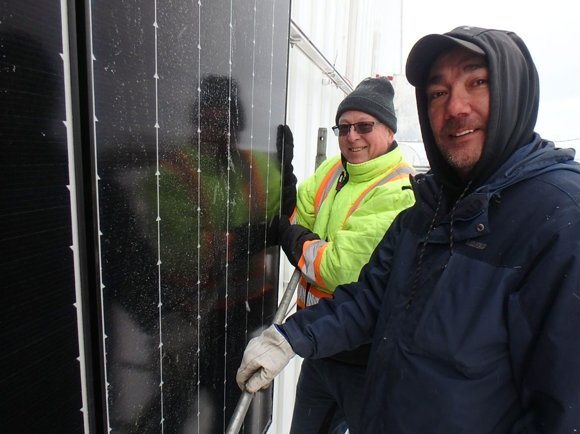 M. Schneider et Christian Christiensen devant un panneau solaire, tournés vers l’appareil-photo et souriants.