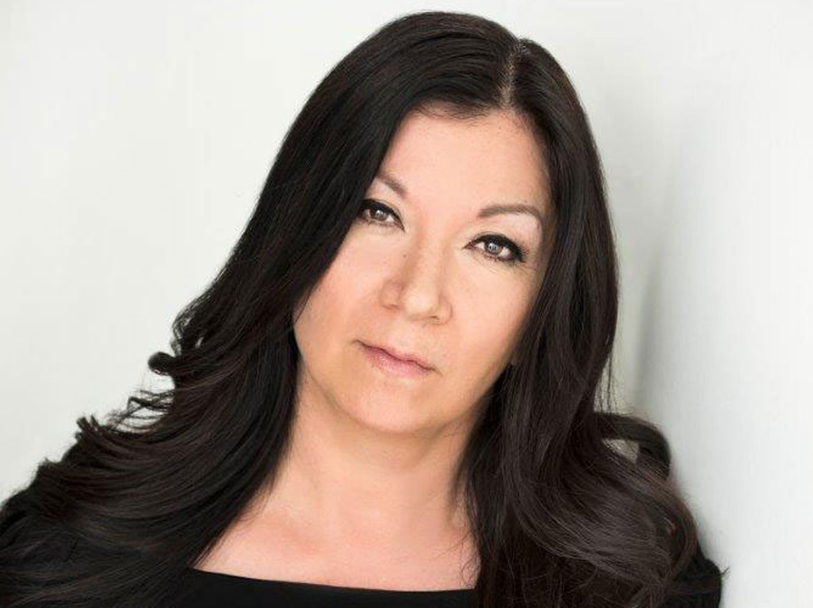 Marie Clements debout devant un fond blanc.