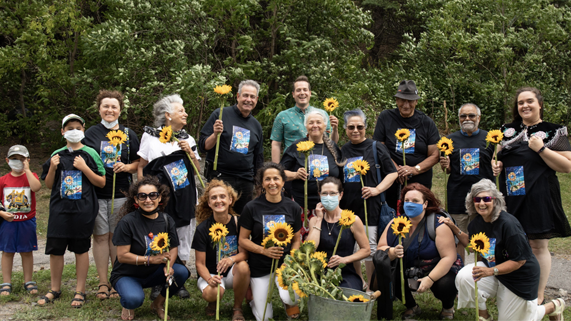 Groupe de bénévoles autochtones et communautaires de la Fresque de la sagesse tenant des tournesols, qui figurent dans la fresque.