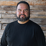 Keith McCrady, souriant, devant un mur lambrissé.