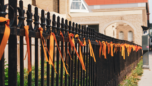Orange ribbons tied to a fence