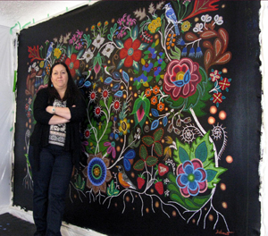 Métis artist Christi Belcourt featured in front of her piece entitled This Painting is a Mirror.