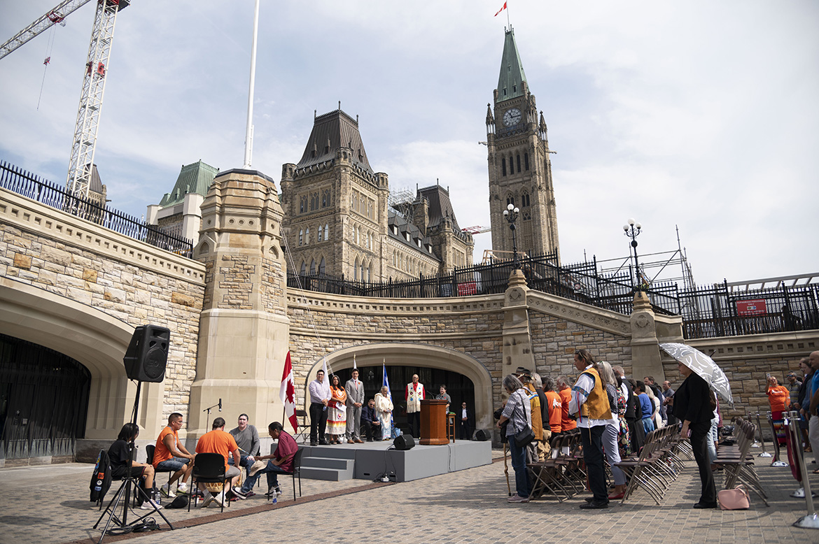 Des personnes jouent du tambour devant les bâtiments du Parlement avant la cérémonie.
