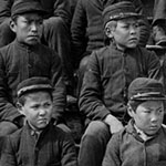 Nineteen Indigenous students seated on the steps outside of the Metlakatla Indian Residential School in British Columbia.