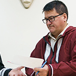 Four people sit at a table to sign the first Inuit coordination agreement.