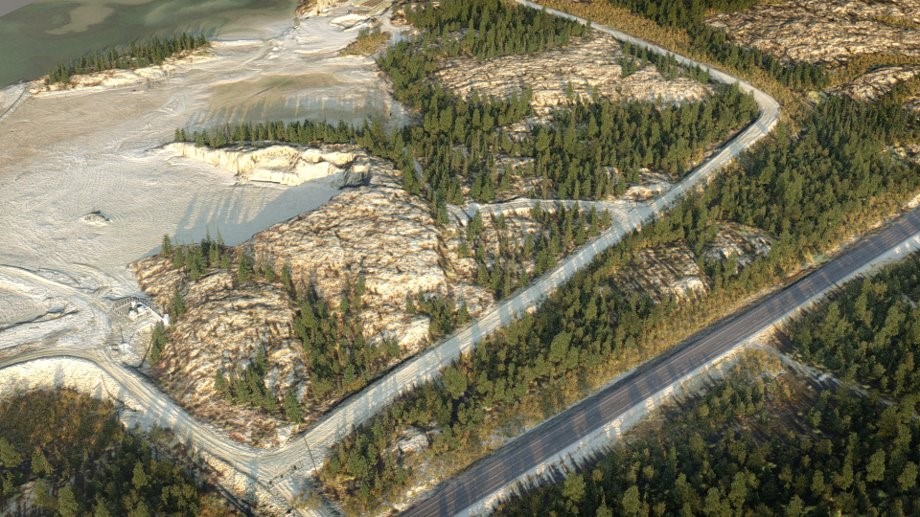 Illustration aérienne d’une zone d’emprunt potentielle sur le site de la mine Giant. Les résidus sont visibles sur le côté gauche de la photo. Un chemin de terre passe entre l’affleurement et les arbres au milieu de la photo, et une route asphaltée bordée d’arbres de chaque côté est visible sur le côté droit de la photo.