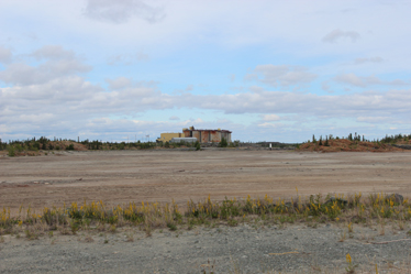 One of the tailings ponds at Giant Mine stretches in front of five large tanks, part of the tailings reprocessing plant.
