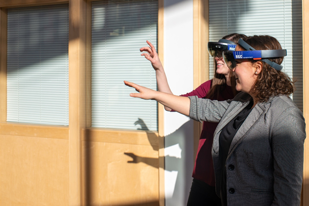 Deux femmes portant des lunettes de réalité virtuelle sont montrées, tendant la main vers ce qu'elles peuvent voir lors de leur expérience.