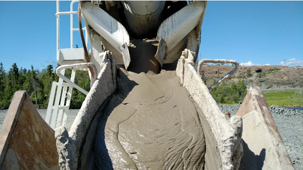 Cette photo montre une substance grise, semblable au ciment, qui s'écoule d'un camion dans une auge afin qu'elle puisse être livrée dans la cavité souterraine.