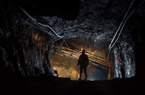 Cette photo montre la silhouette d'un ouvrier dans un tunnel rocheux du sous-sol d'une mine.